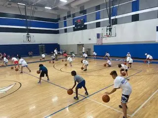 Kids practice basketball in a gym.